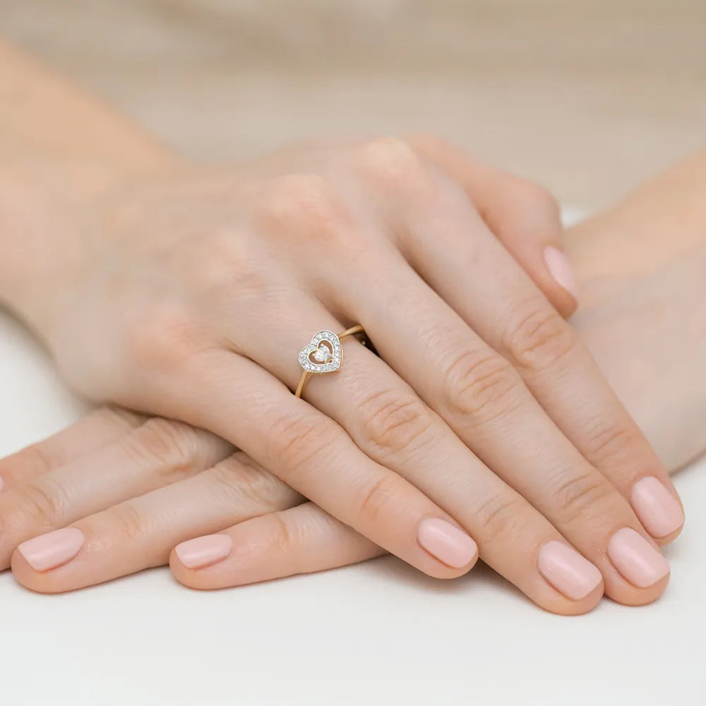 Prsteň zo 14-karátového zlata s diamantom 0,10 ct a 18 diamantmi s celkovou hmotnosťou 0,09 ct. Prsteň je zabalený v čiernej krabičke, papieri a darčekovej taške.
